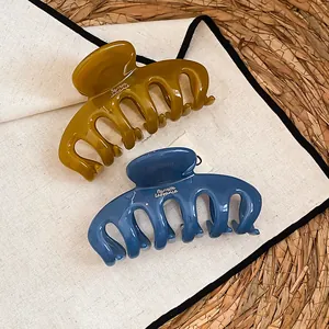 Nahaufnahme von minimalistischen Haarklammern aus Acryl in staubblauem und olivgrünem Design