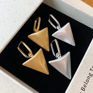 Detail van minimalistische goud- en zilvertinten driehoek oorbellen in geschenkdoos.