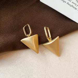 Detailopname van de geborstelde metalen textuur van deze gouden driehoek oorbellen.
