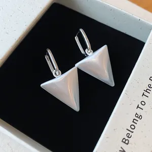 Close-up van elegante zilveren metalen oorbellen met gesatineerde driehoekige hangers