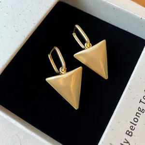 Elegante matgouden driehoekige hanger oorbellen in een zwarte fluwelen juwelendoosje