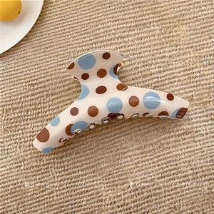 Dettaglio di un elegante fermaglio per capelli in acrilico a pois colorati