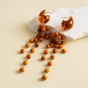Detailed macro view of retro amber resin mottled wood bead tassel drop earrings for women