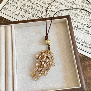 Detailansicht einer edlen Vintage-Muschel-Quastenkette mit Goldperlen und Kordel.