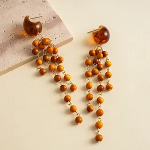 Detail of vintage amber resin earrings with multi-strand wooden bead tassels.