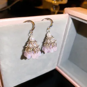 Gros plan de boucles d'oreilles bohèmes à pompons avec cristaux roses et oxydes de zirconium.