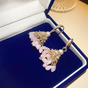 Détail de boucles d'oreilles bohèmes avec cristaux roses et zircons dans un écrin.
