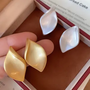 Detailaufnahme eleganter Ohrstecker aus gebürstetem Metall in Blattform, Gold und Silber.
