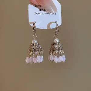 Détail de boucles d'oreilles bohèmes en cristal de zircon et glands avec perles dorées