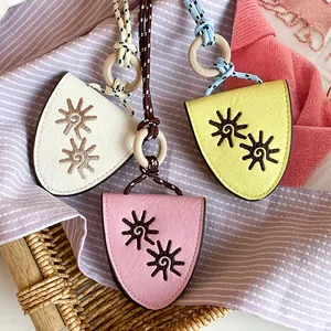 Detailed view of handmade leather sunflower eye pendants with colorful ropes and wooden rings