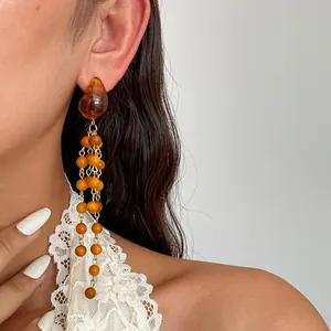 Detailed macro shot of vintage-style resin and wooden bead tassel earrings worn by model
