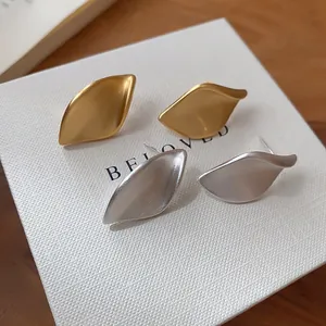 Nahaufnahme von gebürsteten Metall-Ohrsteckern in Blattform in Gold und Silber