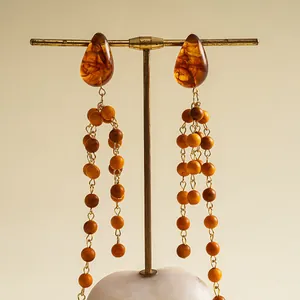 Detail of retro resin teardrop earrings with dangling wooden bead tassels