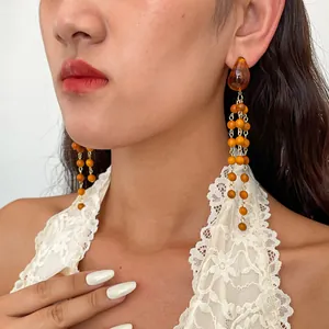 Close-up detail showing retro resin and wooden bead tassel earrings worn by a female model.