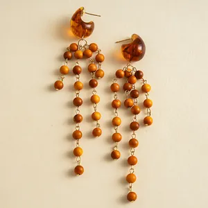 Detailed macro shot of vintage amber resin and tiered wooden bead tassel drop earrings