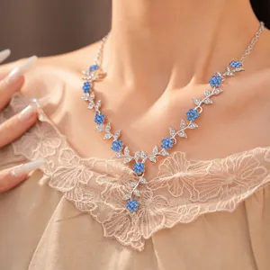 Close-up van een elegante ketting met blauwe kristallen bloemen en zilveren bladeren.