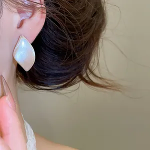 Detailansicht eleganter blattförmiger Ohrstecker mit metallisch gebürsteter Textur.
