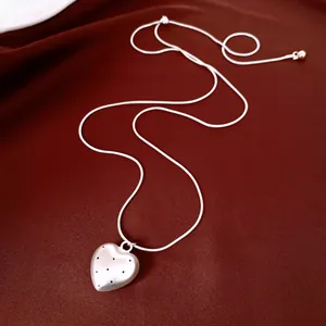 Dettaglio di una collana con ciondolo a cuore color argento con motivi a pois neri