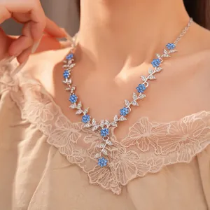 Close-up detail van de ketting met bladmotieven en blauwe strass bloemen voor dames