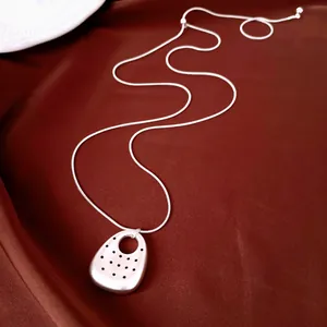 Vista ravvicinata dettagliata della collana con ciondolo ovale in argento con motivo a pois