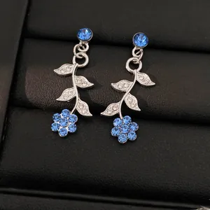 Elegante oorbellen met blauwe bloemen en bladeren en glinsterende strass-steentjes