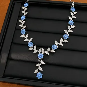 Close-up van een elegante ketting met blauwe kristallen bloemen en zilveren bladeren in een doos