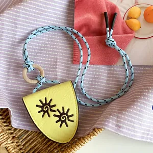 Macro detail of the yellow leather pendant with embroidered sun symbols and blue rope cord.