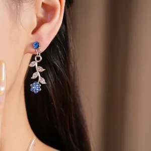 Close-up van elegante zilverkleurige oorbellen met blauwe bloemen- en bladaccenten van strass