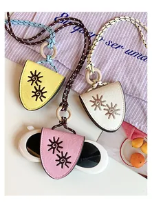 Detailed view of leather eyeglass pouches with embroidered sun motifs and woven cords.
