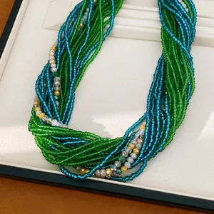 Gros plan de perles de verre multi-rangs vert et turquoise pour un collier à plusieurs fils.