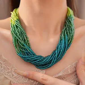 Détail d'un collier multicouche en perles de verre dégradé vert et bleu sur un mannequin