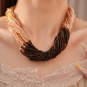Gros plan d'un collier élégant en perles de verre multicouches aux tons dorés et marron torsadés.