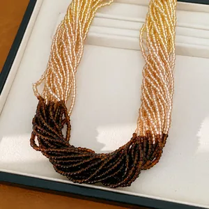 Détail d'un collier multicouche en perles de verre avec dégradé de tons ambrés et jaunes.