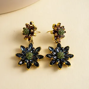 Detailopname van vintage goudkleurige oorbellen met blauwe en groene kristalbloemen