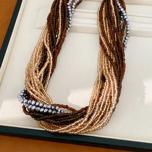 Gros plan d'un collier multi-rangs avec des perles en verre marron, dorées et argentées.