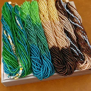 Détails d'un collier multicouche en perles de verre colorées sur plateau de présentation.