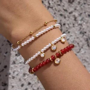 Detailed view of stacked stainless steel bracelets with red agate and pearl beads