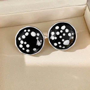 Macro view showing the glossy black and white polka dot pattern on round stud earrings