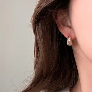 Nahaufnahme eleganter Creolen aus Roségold mit funkelnden Zirkonia am Modellohr.