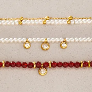 Macro view of layered stainless steel bracelets with red beads and white pearls