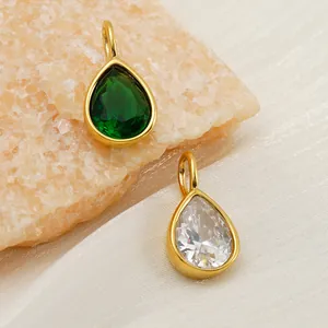 Close-up of gold-plated waterdrop pendants with emerald green and clear cubic zirconia stones.
