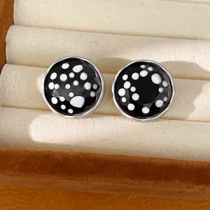 Detailed view of round polka dot glass stud earrings with silver needles in jewelry box