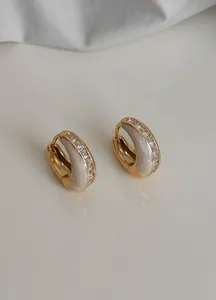 Detailansicht von vergoldeten Creolen im Vintage-Stil mit weißem Inlay und Zirkonia