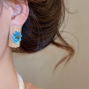 Gedetailleerd vooraanzicht van een luxe blauwe ovale zirkoon oorbel met textuurbasis