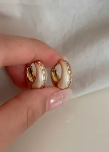 Nahaufnahme goldener Vintage-Ohrringe mit glitzerndem Zirkonia und Perlemail-Inlay-Detail