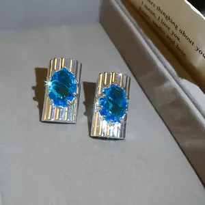 Detail van ijsblauwe ovale zirkonia oorbellen met een zilveren gestreepte basis