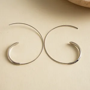Close-up shot of minimalist silver C-shaped geometric ear hooks with a sleek metal finish