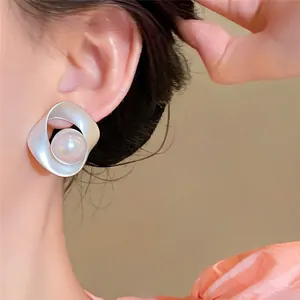 Primo piano dettagliato di orecchino in argento intrecciato con perla indossato all'orecchio
