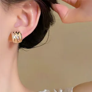 Elegante, quadratische Ohrstecker in Roségold mit Diamantschliff am Ohr eines Models.