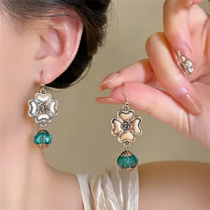 Detailed view of vintage palace style flower earrings with teal green glass bead charms